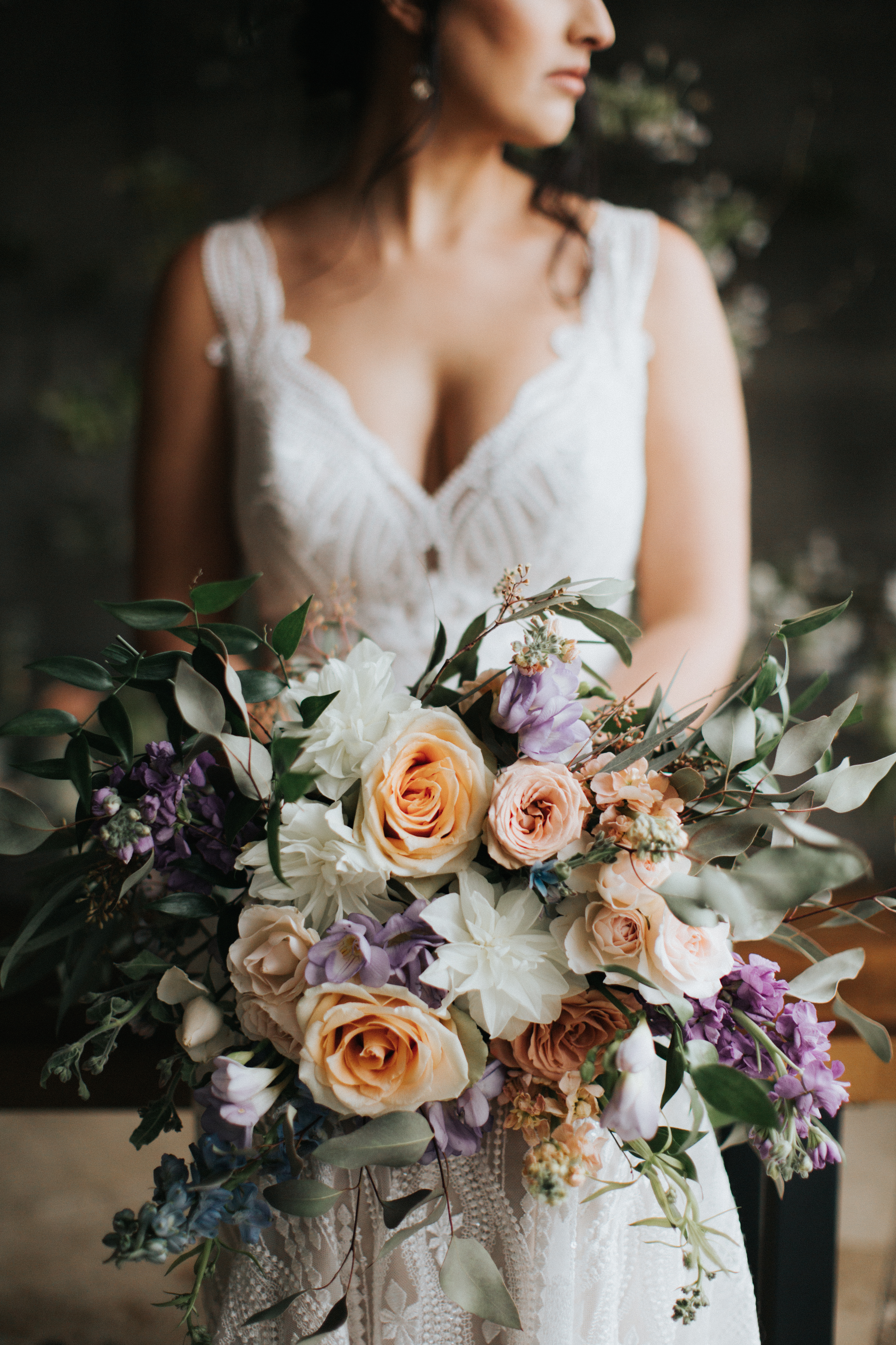 bride holding peach, white, and lavender bouquet