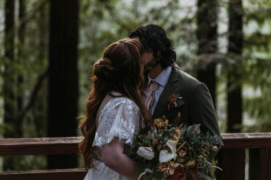 Bride and Groom kissing at hoyt arboretum with wedding flowers